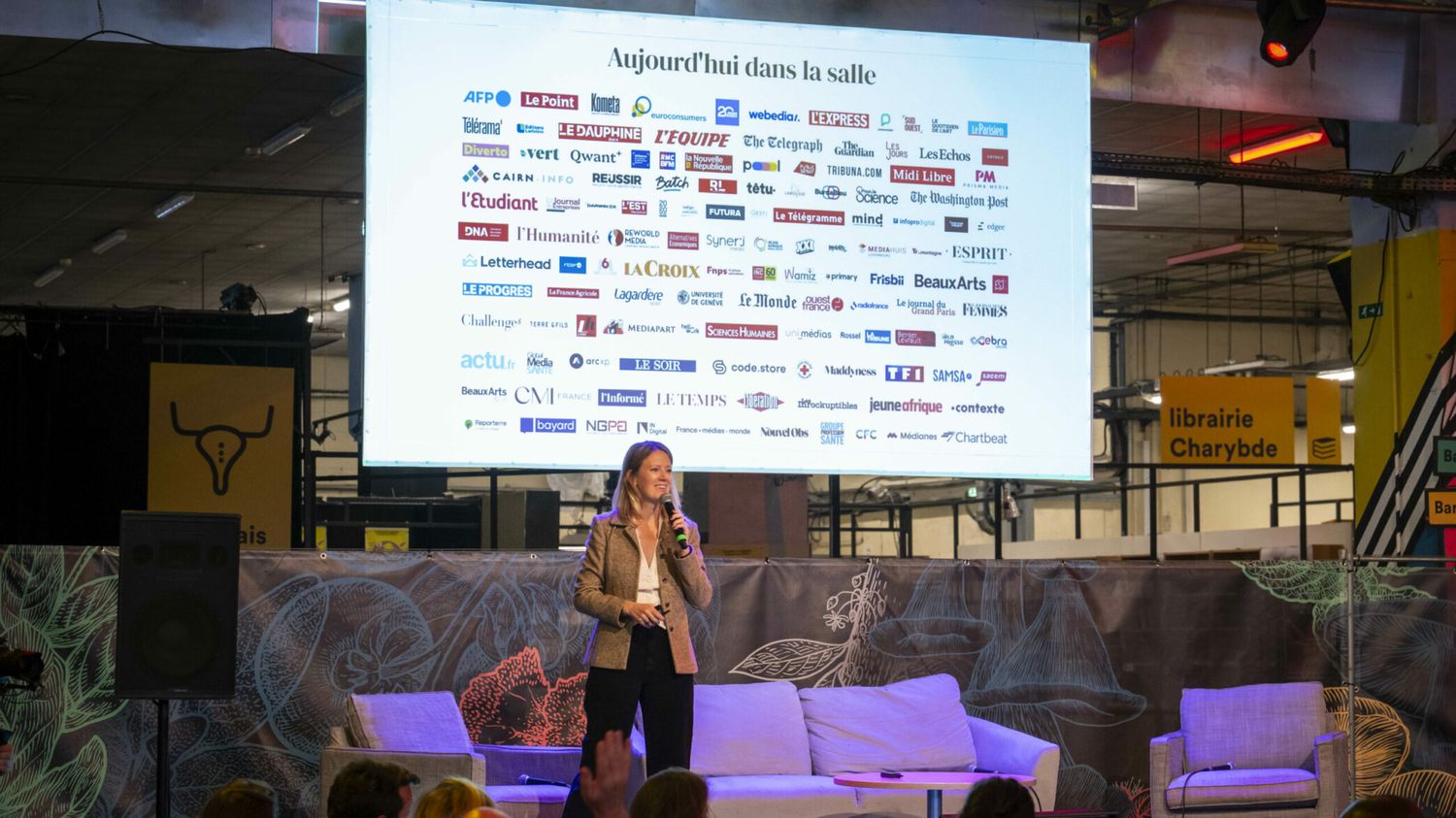 On stage at an Audiencers Festival, a slide listing the titles in the room: AFP, Le Monde, The Guardian, The Washington Post, L'Equipe, Les Echos and more than a hundred others.
